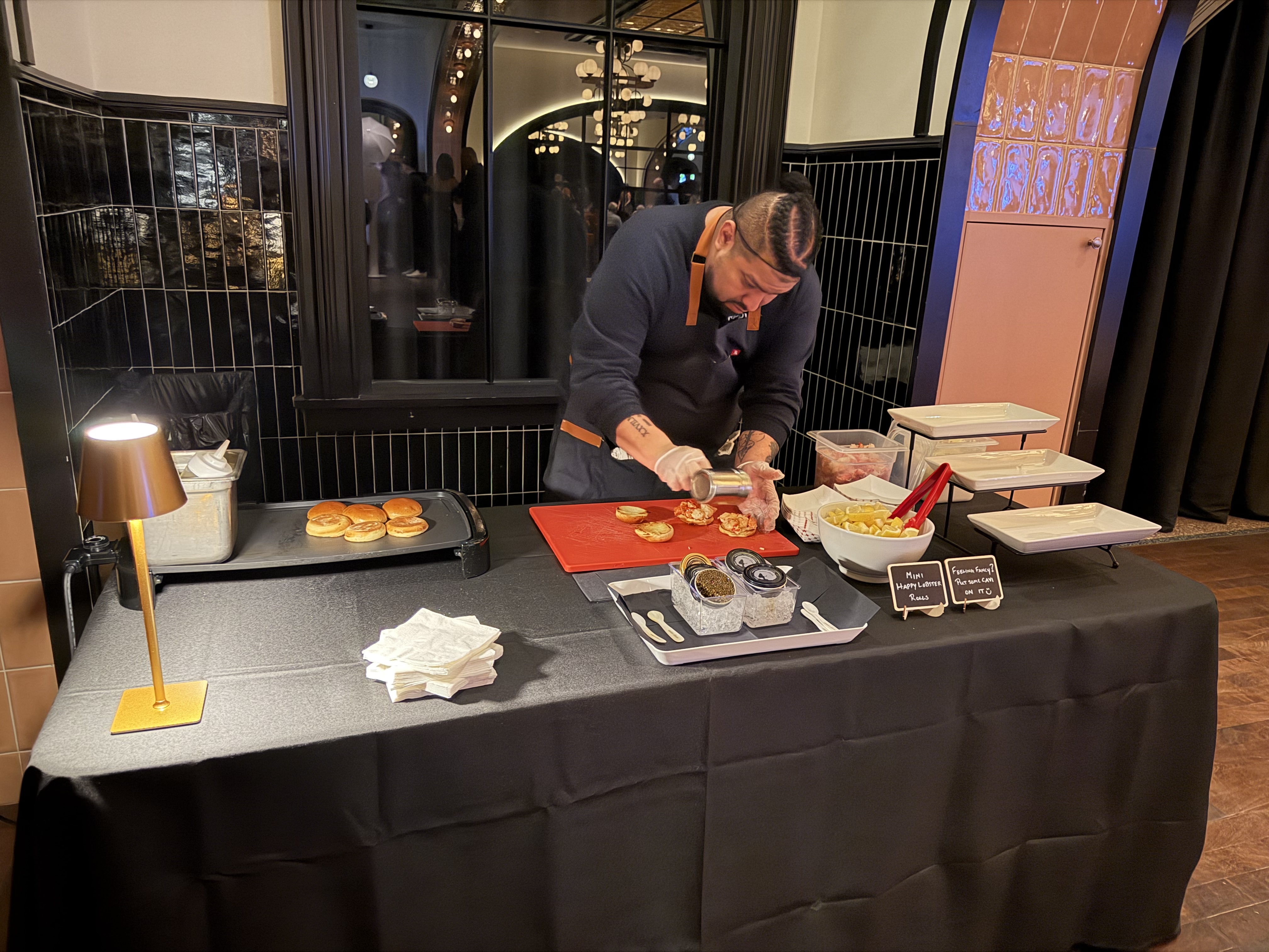 Chef plating lobster rolls at an on-site Happy Lobster Bar